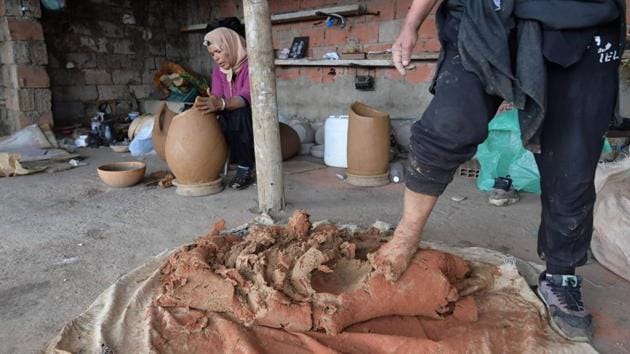 Ayari seen mixing the clay with crushed brick, prepared by her sister-in-law, to strengthen the raw material. The bricks are a rare nod to modern methods, as in the past shattered old pots were used. After a days long drying process, the pots are varnished with a thin coat of white clay. Some are then decorated with red-ochre earth.  (Fethi Belaid / AFP) 