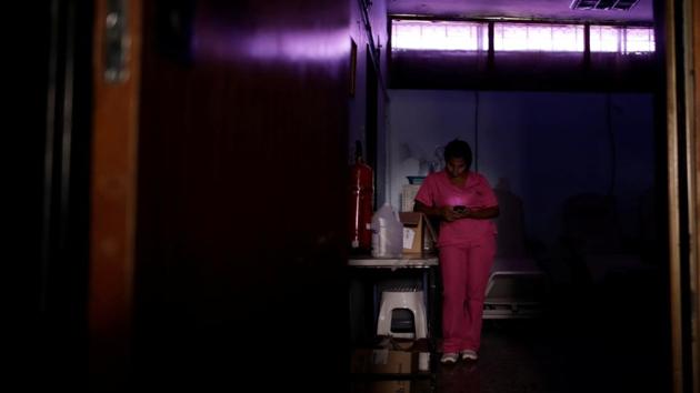A nurse uses a mobile phone while she waits for the electricity to return in a dialysis centre, during a blackout. Maduro says healthcare problems are caused by U.S. sanctions that blocked funds in foreign bank accounts that could be used to pay for imports of equipment and medicine. He says the recent power outages are the result of Washington-backed sabotage of the electrical system. (Ueslei Marcelino / REUTERS)
