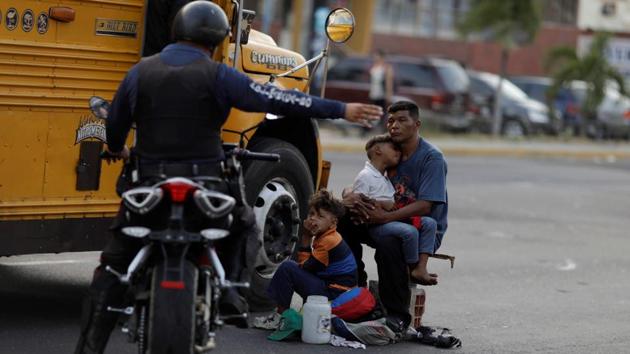A Venezuelan police officer orders a man and his sons to move from the street where he was asking for donations, during a blackout. Some private Maracaibo dialysis centers charge patients $70 for a three-hour session, said 48-year-old kidney-disease patient Antonio Briceno. That is equivalent to nearly a year of minimum wage. (Ueslei Marcelino / REUTERS)