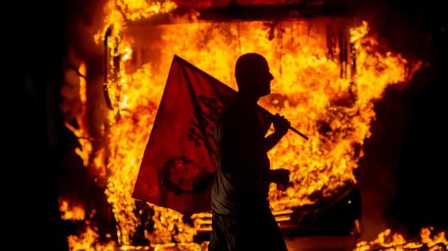 A man holds a flag depicting former Brazilian President Luiz Inacio Lula da Silva past a bus in flames during a protest organized by the National Students Union (UNE) in Rio de Janeiro. (Mauro Pimentel / AFP) A man holds a flag depicting former Brazilian President Luiz Inacio Lula da Silva past a bus in flames during a protest organized by the National Students Union (UNE) in Rio de Janeiro. (Mauro Pimentel / AFP)