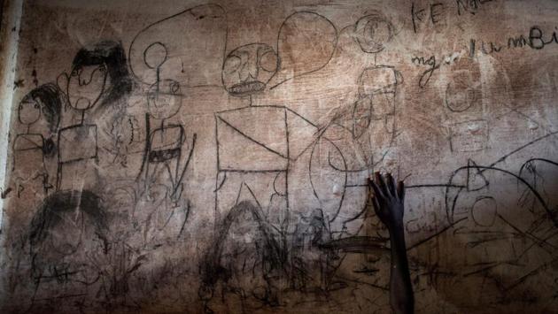 A young South Sudanese refugee's hand is seen in front of a wall filled with drawings and writings depicting scenes from home in Aru, at a refugee transition camp in the Democratic republic of the Congo. (John Wessels / AFP) A young South Sudanese refugee's hand is seen in front of a wall filled with drawings and writings depicting scenes from home in Aru, at a refugee transition camp in the Democratic republic of the Congo. (John Wessels / AFP)