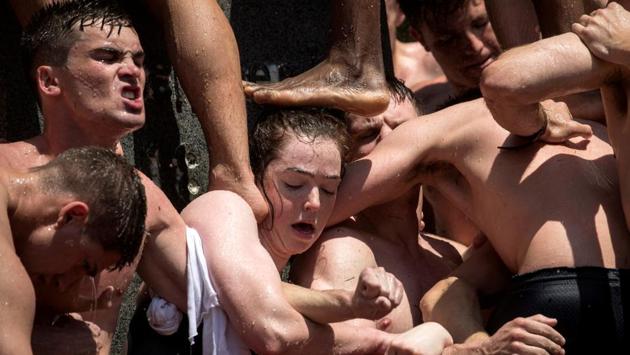 A woman supports her fellow plebes (freshmen) as they build a human pyramid to climb the 21-foot vegetable-shortening covered Herndon Monument at the US Naval Academy in Annapolis, Maryland. The midshipman who makes it to the top replaces the ‘dixie cup’ hat with a midshipman’s hat, marking their class ascent to upperclassmen. (Kevin Lamarque / REUTERS)
