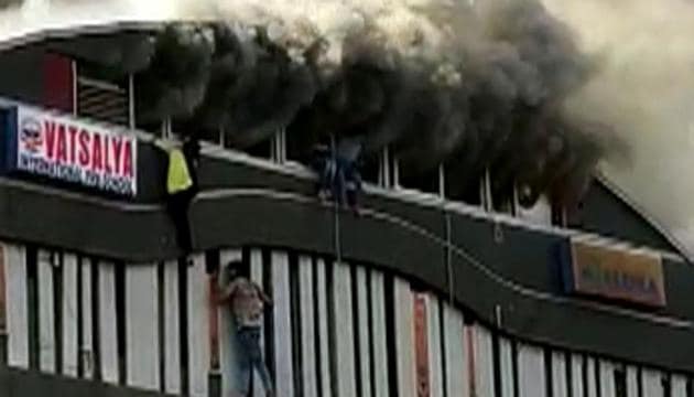 Students jumping out of windows from the top floor of the four-storey building to escape the blaze after a fire broke out on the second floor of a building in Sarthana area of Surat on Friday.(ANI photo)