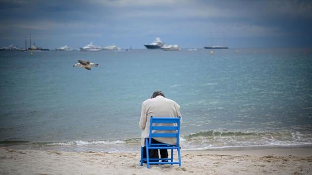 A seagull flies as a man sits by himself on a chair on a beach during the 72nd edition of the Cannes Film Festival in Cannes, southern France. (Olivier Morin / AFP)