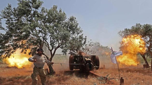 A Syrian fighter from the Turkish-backed National Liberation Front (NLF) fires a heavy artillery gun from the rebel-held Idlib province against regime positions in the northern part of Hama province, Syria. (Omar Haj Kadour / AFP)