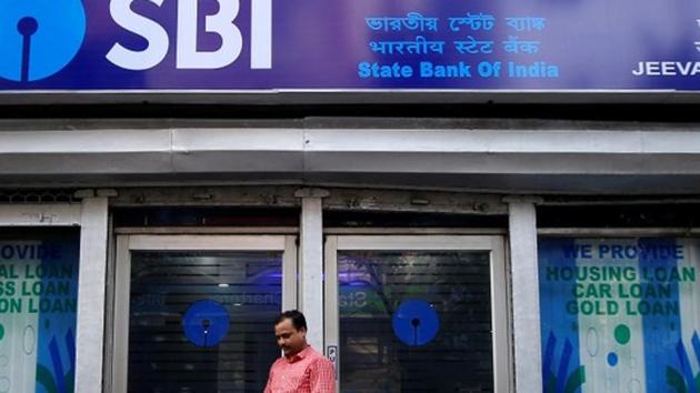 A man checks his mobile phones in front of State Bank of India (SBI) branch(REUTERS)