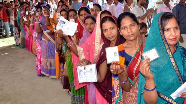 Voters show their ID cards as they wait in a queue to cast vote at a polling station.(ANI Photo)