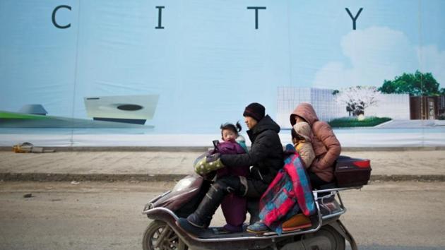 A family rides a scooter past a billboard advertisement of an apartment complex near the new stadium. Attracted by cheaper prices in interior provinces like Henan, buyers from across the country piled into Zhengzhou, many paying in full, in cash, to secure flats that often sold out within minutes. (Thomas Peter / REUTERS) A family rides a scooter past a billboard advertisement of an apartment complex near the new stadium. Attracted by cheaper prices in interior provinces like Henan, buyers from across the country piled into Zhengzhou, many paying in full, in cash, to secure flats that often sold out within minutes. (Thomas Peter / REUTERS)