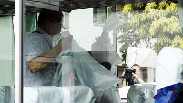 An investigator holds plastic bags containing school students' belongings inside their school bus at the scene where a man wielding a knife attacked commuters in Kawasaki, near Tokyo Tuesday.(AP Photo)