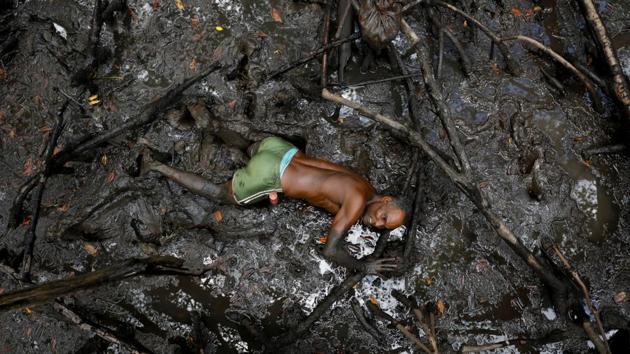 Jose catches crabs inside the mangrove forests. With passing time. he begins to blend into his surroundings, becoming increasingly caked in mud, lying flat and submerged shoulder deep in the mud that is fertile grounds for the crabs he seeks. (Nacho Doce / REUTERS) 