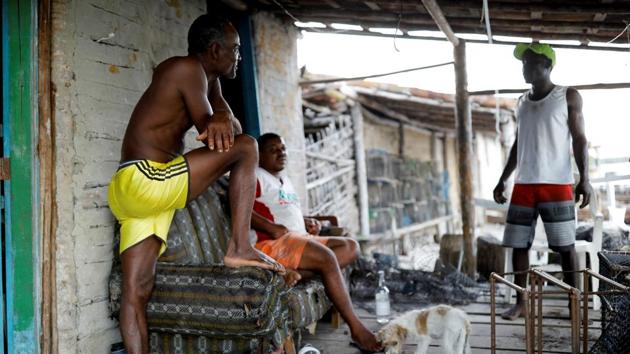 Jose, who is known by the nickname ‘Vampire’ because of his distinctive teeth, talks with neighbours outside his house. The tenuous livelihood of fishermen like Cruz is facing a series of threats, including rapid alterations to the environment caused by climate change. (Nacho Doce / REUTERS) 