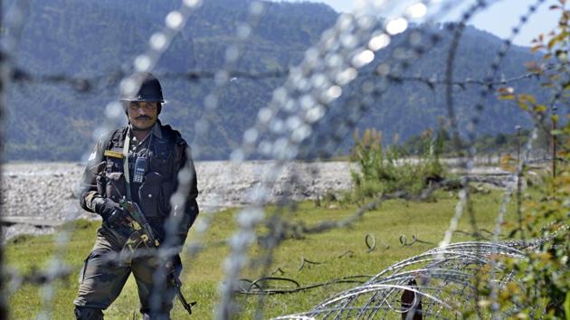 An Indian Army soldier patrols on the fence near the India-Pakistan LOC in Chakan-da-Bagh area near Poonch.(HT Photo)