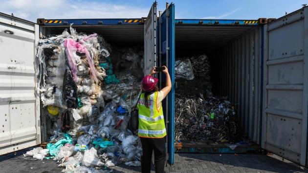 A member of the media takes pictures of containers filled with plastic waste before shipping back to the country of origin in Port Klang, west of Kuala Lumpur, Malaysia. (Mohd Rasfan / AFP)