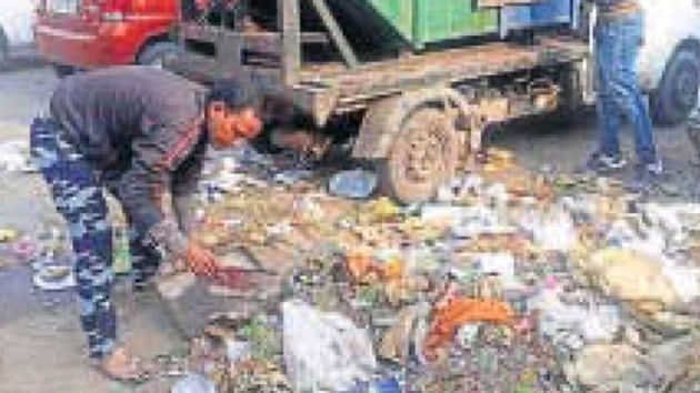 Sanitation workers collect waste in a vehicle.(HT file photo)