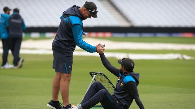 Pakistan all-rounder Mohammad Hafeez (R) is helped to his feet by Pakistan's head coach Mickey Arthur.(AFP)