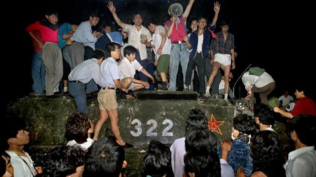 Civilians stand on a government armoured vehicle in Beijing early June 4, 1989. Having decided that armed force was needed to end the protests, the leadership ordered in the army, a move that sent in an estimated 180,000 troops and police. City hospitals filled up with the dead and wounded. Hundreds, possibly thousands, were believed killed in Beijing and other cities during the night and in the ensuing roundup. (Jeff Widener / AP File)