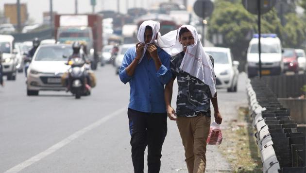 People cover themselves to beat the heat on a summer day, in Gurugram.(Yogendra Kumar/HT PHOTO)