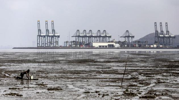 Gantry cranes operated by PSA International Pte stand at the Jawaharlal Nehru Port while a fisherman gathers shellfish. The Trump administration has said concerns over market access for US goods being exported to India led them to withdraw the benefits, which prohibited duties on about $5.7 billion in imports in 2017, according to the Congressional Research Service. (Dhiraj Singh / Bloomberg)