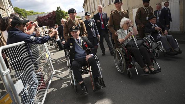 A spectator shakes the hand of a British veteran who is part of a procession leaving the Bayeux Cathedral. Gratitude was a powerful common theme. Up to 12,000 people gathered hours later at the ceremony at the Normandy American Cemetery, where Macron and Trump spoke. US veterans, their numbers fast diminishing as years pass, were the guests of honour. (Francisco Seco / AP)