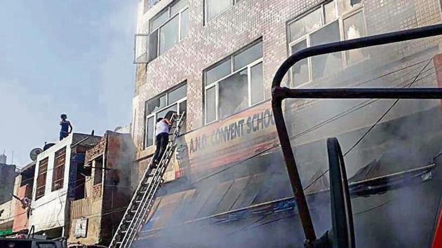 A man climbs a ladder to rescue occupants of a three-storey building, which houses a garments store, a playschool and a home, engulfed in flames and smoke at Dabua Colony in Faridabad. (Subhash Sharma/HT) A man climbs a ladder to rescue occupants of a three-storey building, which houses a garments store, a playschool and a home, engulfed in flames and smoke at Dabua Colony in Faridabad. (Subhash Sharma/HT)