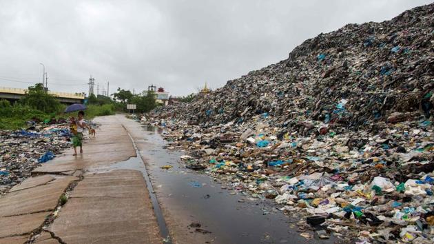 A woman carries a child as she walks past a garbage dump on the outskirts of Yangon, Myanmar. (Sai Aung Main / AFP) A woman carries a child as she walks past a garbage dump on the outskirts of Yangon, Myanmar. (Sai Aung Main / AFP)