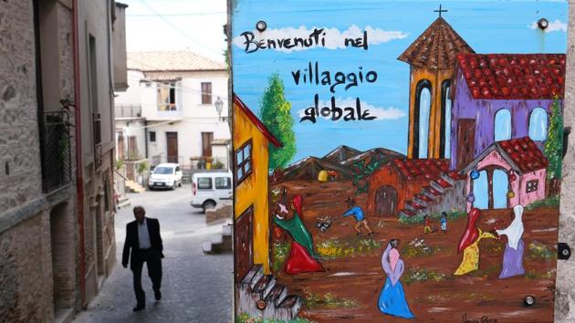 A hand painted road sign “Welcome to the Global Village” still hangs in the small town, but its dream of migrant integration is over after the far-right’s “Italians first” election victory. (Alberto Pizzoli / AFP) 