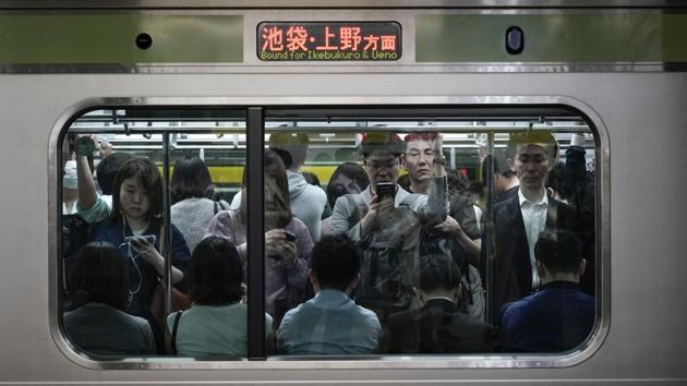 Commuters stand in a packed Yamanote Line train while waiting for the train at Shinjuku Station in Tokyo. The trains are so densely packed during morning and evening rush hours that passengers don’t need to hold onto a handrail to avoid falling. There are shoves from commuters who can’t wait three to four minutes for the next train, but no one growls in irritation. It’s typically forgiven with a little nod, a gesture of apology. (Jae C. Hong / AP)