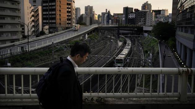 A man walk on the bridge as a Yamanote Line train departs from Ikebukuro Station in Tokyo. If a commuter misses its station, then he will return 28 stations later, or else has to get off at any stop and catch a train travelling around the loop in the opposite direction. (Jae C. Hong / AP)