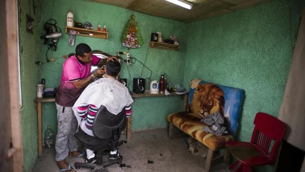 An inmate who runs one of the existing barbershops, cuts the hair of another inmates inside the prison. The prisoners enjoy significant freedom within their confinement: They can largely say what they want, form groups, unions or cooperatives, have a telephone, use the internet and communicate with the outside world, even own a dog. (Matilde Campodonico / AP)