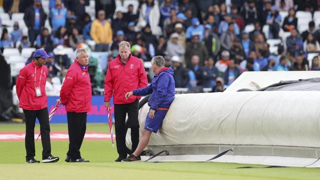 Umpires interact with a groundsman as they inspect the field.(AP)