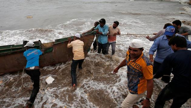 Fishermen move a fishing boat to a safer place along the shore ahead of the expected landfall of Cyclone Vayu at Veraval, India, June 12, 2019.(REUTERS PHOTO)