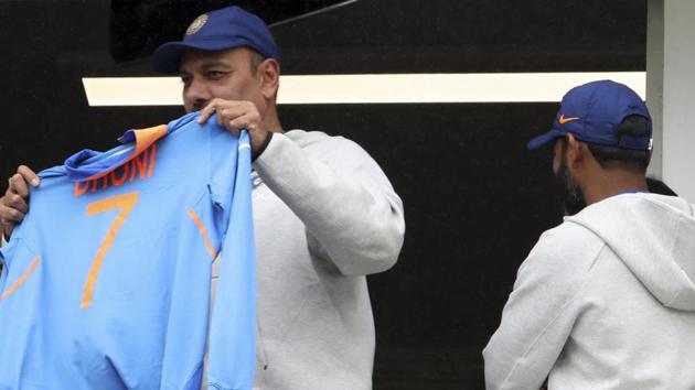 India's coach Ravi Shastri holds MS Dhoni team's jersey whilst standing in the players pavilion.(PTI)