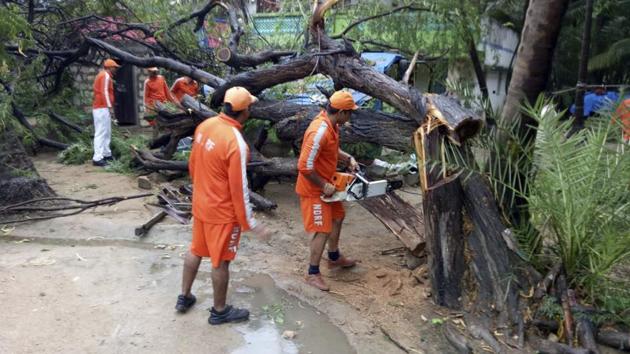 National Disaster Response Force (NDRF) soldiers cut branches of an uprooted tree that fell in the compound of a house from Cyclone Vayu caused winds at Diu. The NDRF has deployed 40 teams in 15 districts of Gujarat, and four teams in Diu. In addition, six teams will be airlifted from Patna and INS Rajali. (NDRF via AP) National Disaster Response Force (NDRF) soldiers cut branches of an uprooted tree that fell in the compound of a house from Cyclone Vayu caused winds at Diu. The NDRF has deployed 40 teams in 15 districts of Gujarat, and four teams in Diu. In addition, six teams will be airlifted from Patna and INS Rajali. (NDRF via AP)