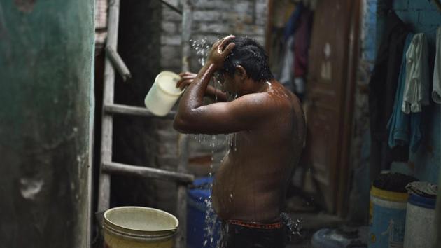A man bathes at his house in Sanjay Colony. There were water taps installed in the area a year back have hardly proved useful. The water from the tankers is instead what ends up fulfilling everyday household needs such as drinking, washing and bathing for most residents. (Burhaan Kinu / HT Photo)