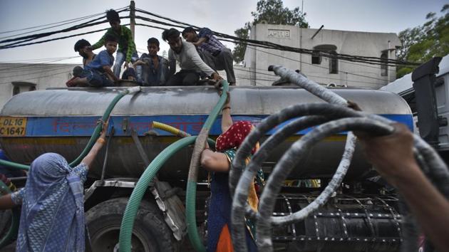 People hand over lengths of hose pipe to be used to fill water from a Delhi Jal Board tanker. Nearly 150 water tankers operate in the area between 6am to 11pm and each tanker carries 8000 litres of water. Raman, a resident of the colony said “Almost every day someone gets injured while filling their buckets from the tankers, there is also danger of falling under the tankers due to heavy rush.” (Burhaan Kinu / HT Photo)