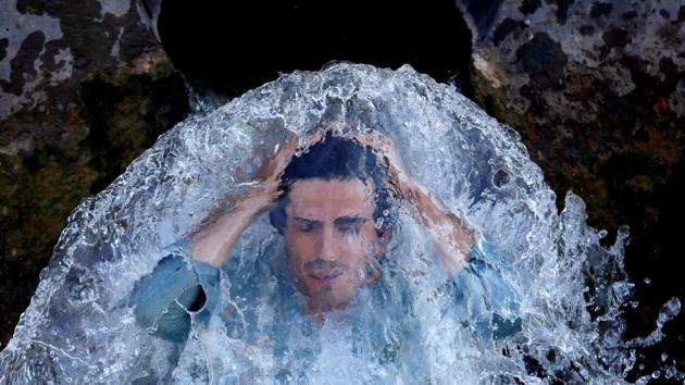 A man cools off under a water pipe from a canal on the outskirts of Peshawar, Pakistan. (Fayaz Aziz / REUTERS)