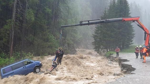 Two occupants of stranded van are lifted unhurt by a crane during heavy rain, in Spluegen, Switzerland. (REUTERS)
