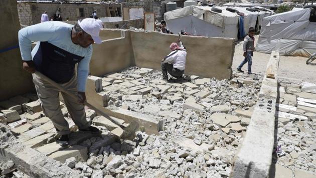 Workers demolishing a concrete shelter at a refugee camp in the northeastern Lebanese town of Arsal, in the Bekaa valley, near the border with Syria. With a government ultimatum looming, the men in the sprawling Al-Nour camp this week took to the roofs of their own cinderblock homes to remove sheets of corrugated iron and start hacking away with sledgehammers. (Joseph Eid / AFP)