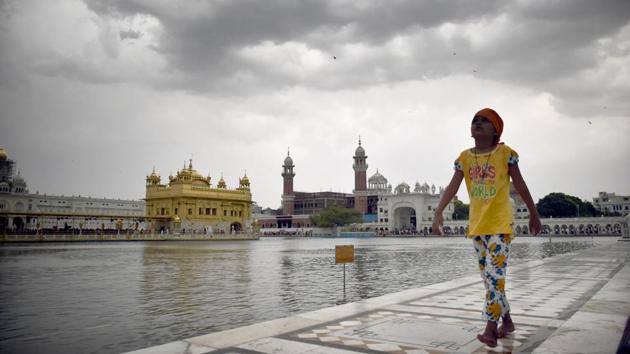 A girl circumambulates the Golden Temple as dark clouds loom over it, in Amritsar, Punjab. (Sameer Sehgal / HT Photo)