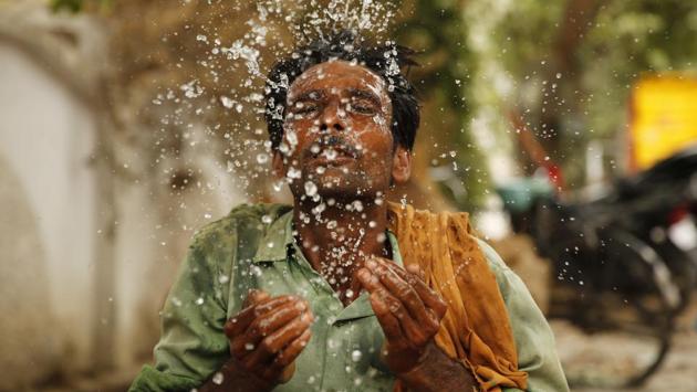 A worker splashes water on his face to cool himself on a hot afternoon at Prayagraj, Uttar Pradesh. (Rajesh Kumar Singh / AP)