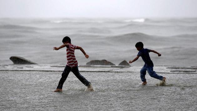 Children play in a puddle of water as it rains at a sea front in Kochi, Kerala. (Sivaram V / REUTERS)