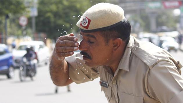 A police personnel washes his face as a respite from the heat, at Z-Chowk, near Huda City Centre metro station. A few officials said that at major junctions, they suffer a lot as there is a need for traffic police at these places throughout the day. They sometimes take refuge inside traffic booths. (Yogendra Kumar / HT Photo)