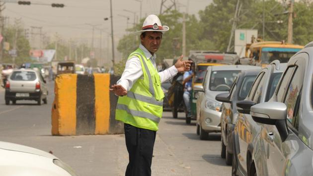 A traffic police officer directs vehicles at Hero Honda Chowk. There are around 1,500 traffic police officials in the city who work in different shifts, which extend beyond 12 hours. (Parveen Kumar / HT Photo)