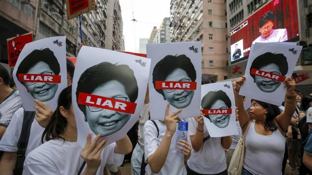 Protesters hold pictures of Hong Kong Chief Executive Carrie Lam as protesters march along a downtown street. (Kin Cheung / AP)