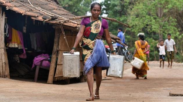 A woman carries water in stainless steel cans at Shakar Pada village. The tanker operators come back, fill up and head out again. Often Dukre doesn’t finish his rounds until 7.30 pm. “It’s hard work but my heart feels good because I am helping people,” he said. (Punit Paranjpe / AFP)
