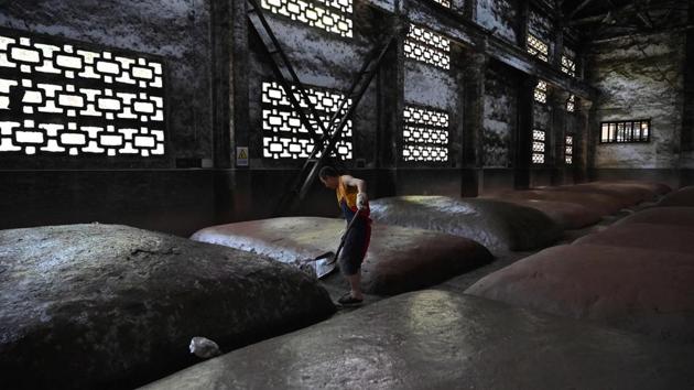 A worker moistens mounds where grain is fermented. Staff, resembling shaolin monks in bright yellow and red outfits and performing all work by hand, distil the fermented mash in steaming-belching wooden pot stills. The end-product is then aged, sometimes for decades, in giant clay pots in nearby caves. (Hector Retamal / AFP) A worker moistens mounds where grain is fermented. Staff, resembling shaolin monks in bright yellow and red outfits and performing all work by hand, distil the fermented mash in steaming-belching wooden pot stills. The end-product is then aged, sometimes for decades, in giant clay pots in nearby caves. (Hector Retamal / AFP)