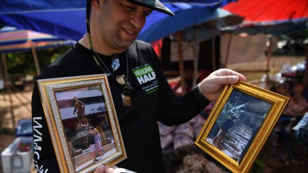 A tourist from the US looking at his souvenir photos taken near the entrance of the Tham Luang cave. Nearby lottery ticket vendors are capitalising on the perceived good fortune linked to the boys’ survival and the folkloric appeal of a nearby shrine. The number of stalls has mushroomed from a few dozen to around 250. (Lilian Suwanrumpha / AFP)