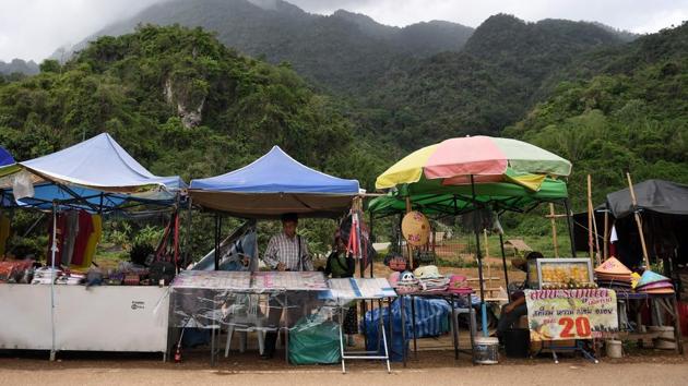 Vendors setting up stalls along the road leading to the Tham Luang cave. Laying white flowers at the foot of his bronze statue, Thai nurse Sumalee, who travelled four hours to the site, described him as “the hero of the whole country” in a sobering reminder of the risks involved in the rescue amid the blizzard of marketing opportunities now attached to the cave story. (Lilian Suwanrumpha / AFP)