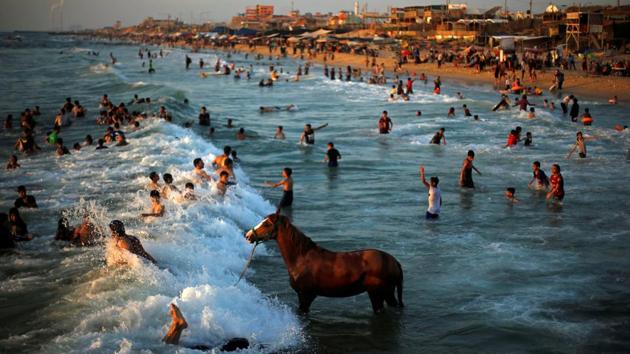 A Palestinian man washes his horse in the waters of the Mediterranean Sea as people swim on a hot day in the northern Gaza Strip. (Mohammed Salem / REUTERS)