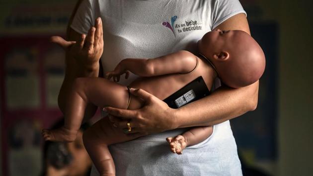 A sex education teacher shows students how to hold a baby, using a baby robot, at a school in Caldas, Colombia. Schoolchildren in Caldas are taking part in a voluntary program using a baby simulator -- a rubber doll with built-in software –programmed to act like a newborn baby in a bid to reduce the high level of teenage pregnancies in the town of 78,000. (Joaquin Sarimento / AFP)
